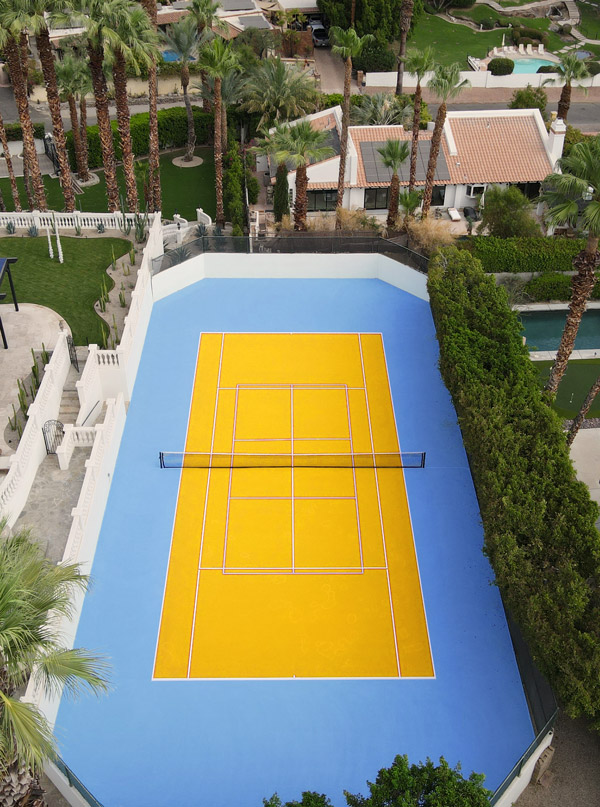 Aerial view of a tennis court featuring a vibrant yellow and blue color scheme, showcasing the court's unique design.