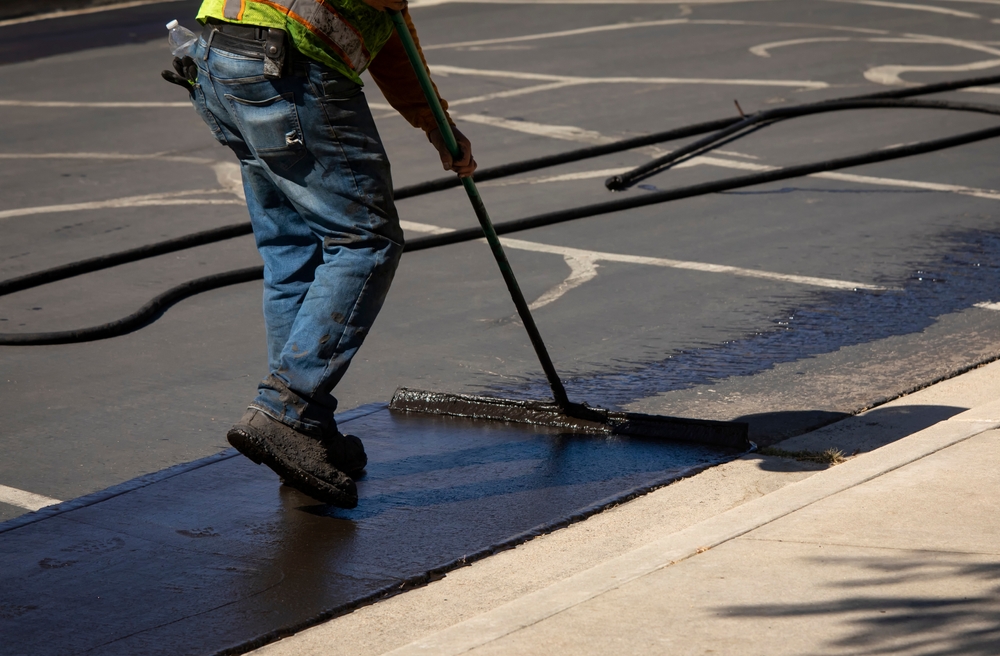 technician resurfacing asphalt with sealant composite