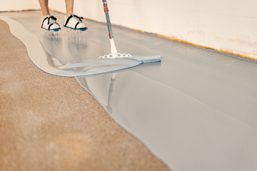 Man applying epoxy flooring to cement.