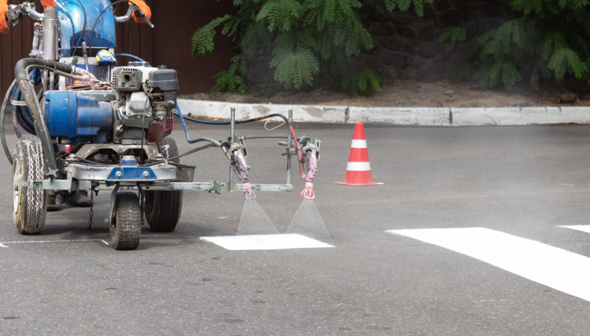 Worker painting stripes on asphalt